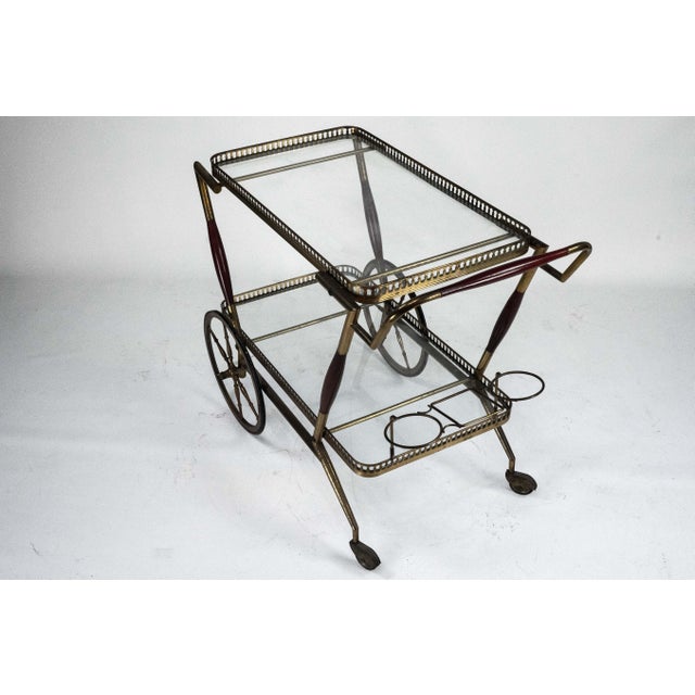 Elegant mid-century Italian bar cart featuring a refined brass frame with pierced gallery details and two clear glass...