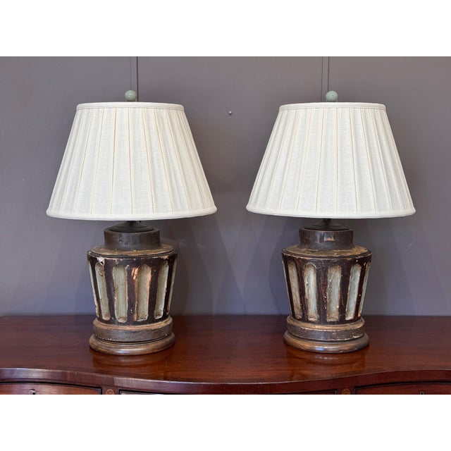 A matched pair of carved wood neoclassical column-form lamps with tapering bodies articulated by vertical fluting, stepped...