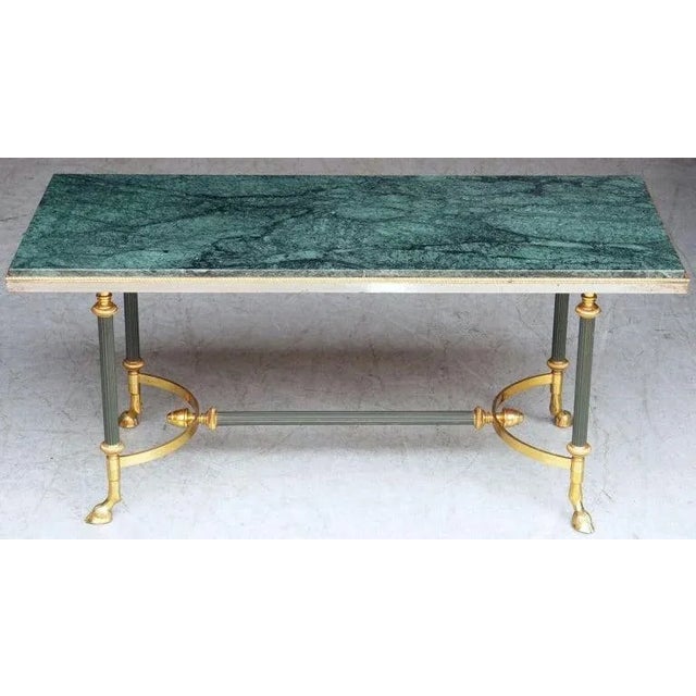 A fine French Mid-Century coffee or cocktail low table of brass and marble attributed to the Parisian interior decoration...