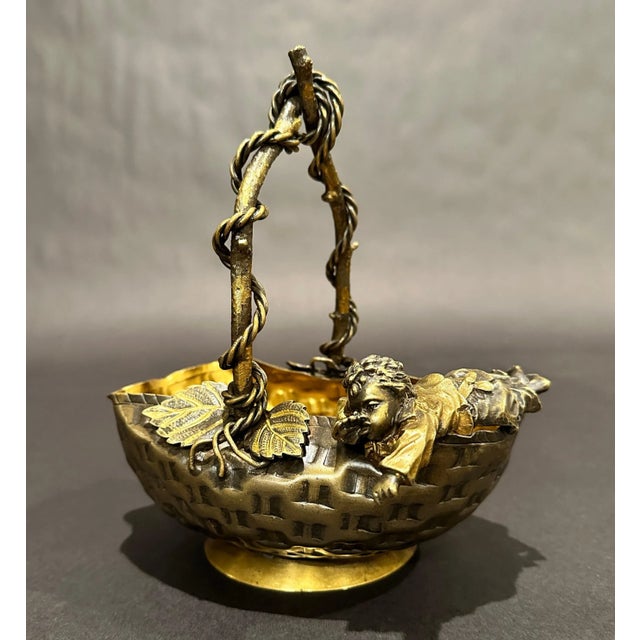 French aesthetic movement patinated and gilt bronze figural center bowl/basket, third quarter 19th century, formed as a...