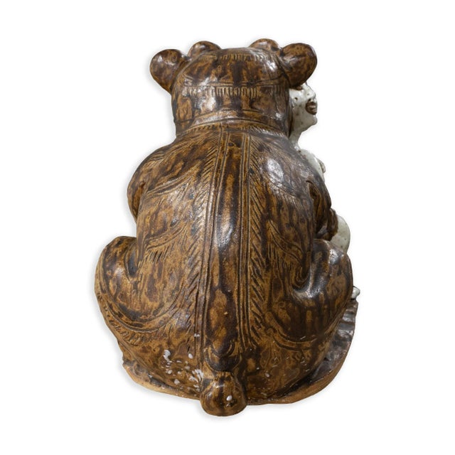 An unusual and expressive antique Asian ceramic sculpture depicting a male figure locked in playful struggle with a...