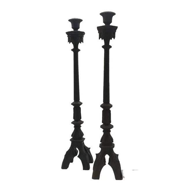 Pair of iron candlesticks in Italian neo-Gothic style with four-foot metal bases. Good overall condition, with excellent...