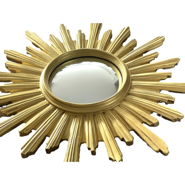 Majestic convex sunburst mirror, also known as a "witch's eye," made of gilded resin, imitating wood. A striking...