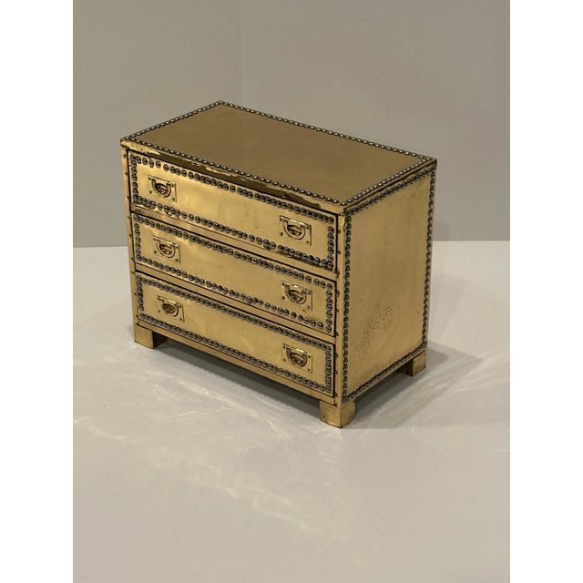 Small captivating brass over wood small chest having 3 drawers and nailhead decoration with recessed handles.