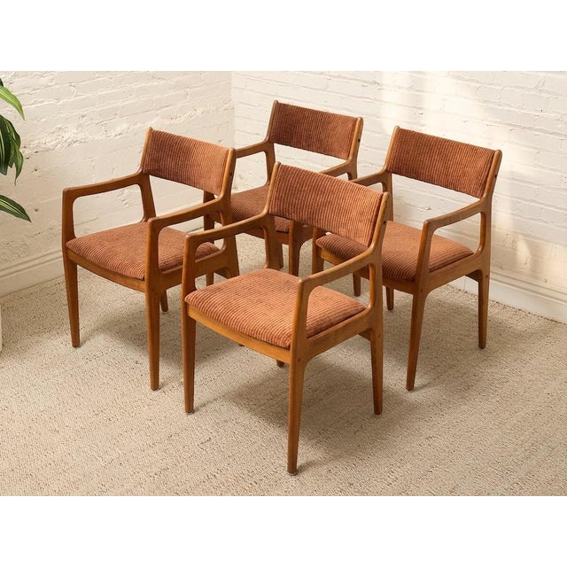 A handsome set of four vintage Danish modern dining chairs featuring sculpted warm wood frames and rich rust-toned...