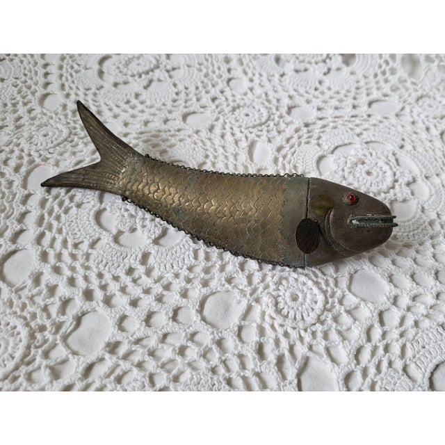 A mid century French brass fish figurine, measuring 8” x 1 ¾” x 2 ¼” d. Hold it by it's tail and watch it wiggle. Found in...