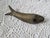 A mid century French brass fish figurine, measuring 8” x 1 ¾” x 2 ¼” d. Hold it by it's tail and watch it wiggle. Found in...