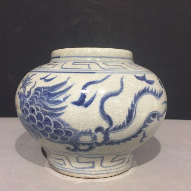 A charming and highly decorative small porcelain jar featuring a dynamic blue dragon design. This piece showcases a...