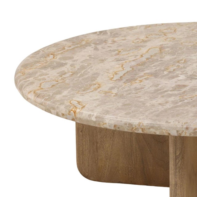Round beige-toned Tendu marble coffee table featuring a substantial stone top supported by a sculptural natural mango wood...