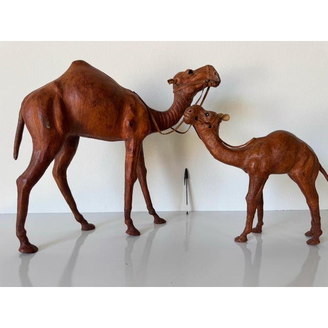 Charming pair of vintage handcrafted leather camel sculptures, featuring a striking mother and baby duo. Each camel is...