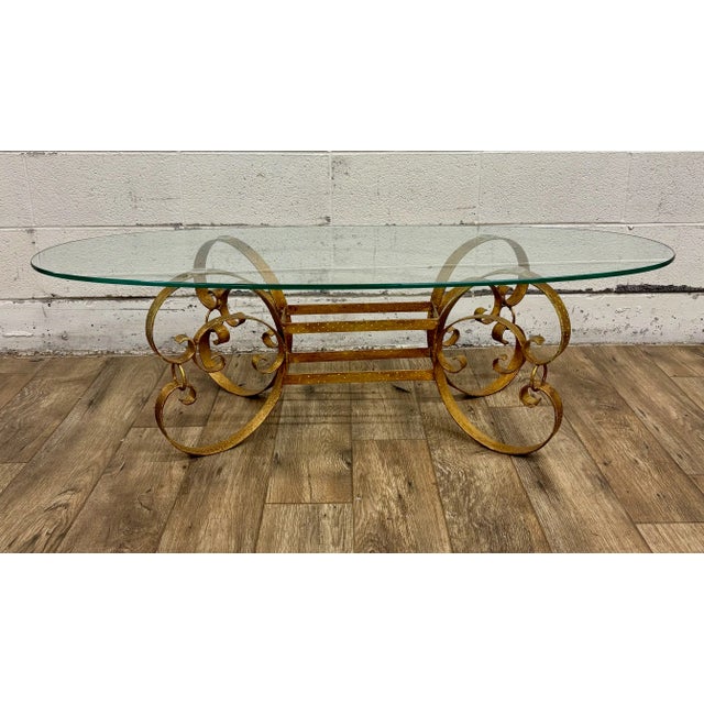 This is a gorgeous vintage Hollywood Regency gold wrought iron glass top oval coffee table or cocktail table with scrolled...