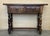 panish console table with two carved drawers, with iron handles that stand on four legs in the shape of domed columns and...