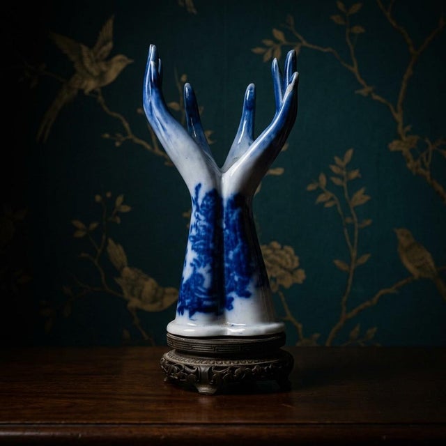 A captivating and highly unique antique porcelain sculpture vase with two holes, featuring two stylized hands reaching...