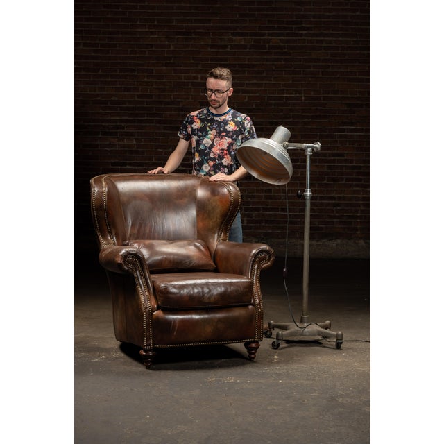 c. 1990s; Walter E. Smithe Furniture and Design - Itasca, IL Wingback-style leather armchair with ottoman and pillow....