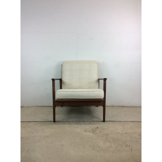 This Danish modern lounge chair features hardwood construction, original walnut finish, vintage white cushions, and...