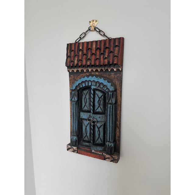 A wonderfully distinctive signed Brazilian carved wood wall sculpture dating to 1979, depicting a colorful architectural...