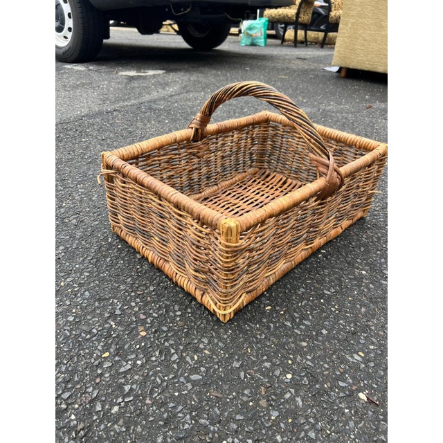A charming woven rattan basket featuring a sturdy rectangular form and arched handle, perfect for storage, display, or...