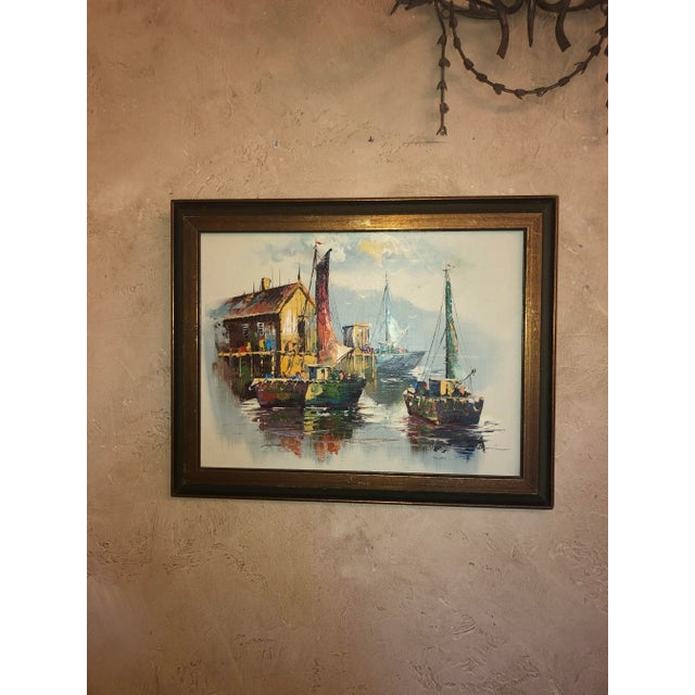 A peaceful yet colorful mid century painting of sailboats near the boathouse. In a dark wood frame.