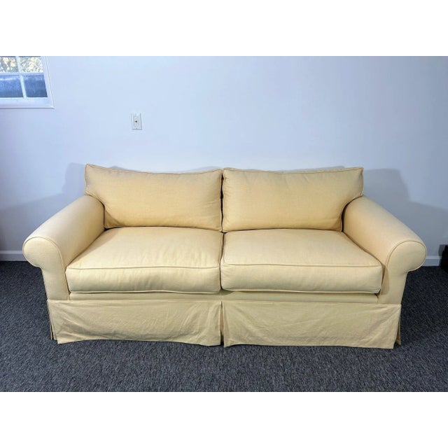 A custom, well-made two-seat sofa with a hardwood frame, classic rolled arms, loose down-filled cushions, and dressmaker...