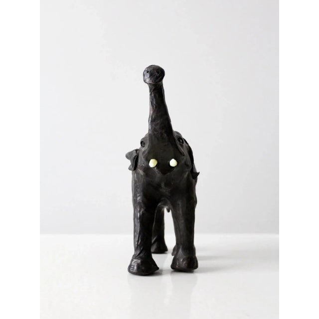 This is a vintage leather elephant sculpture. The hand-crafted figure features beautifully aged black leather with glass...