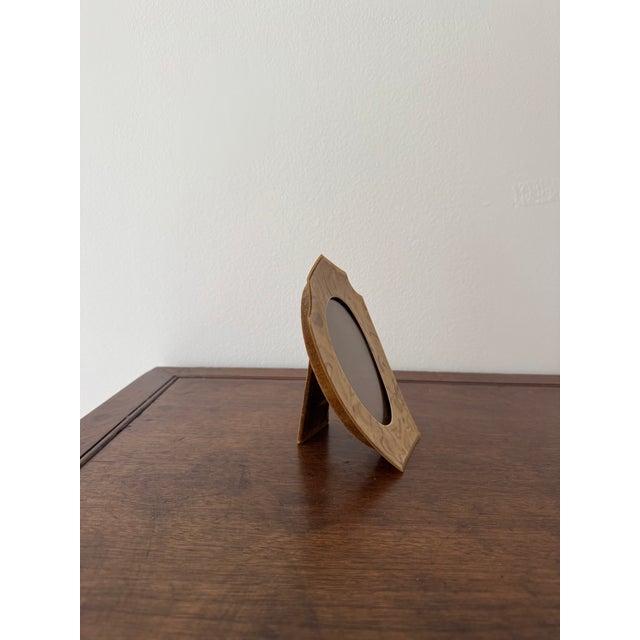 Beautiful vintage tabletop picture frame featuring a faux burlwood finish and a classic oval opening. Era: 1978–1988 (most...