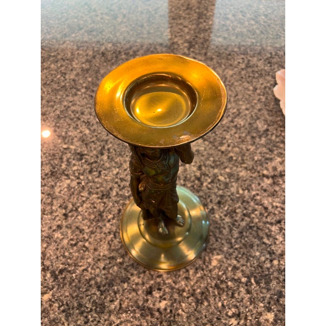 Overview: Striking Egyptian Revival brass candlestick featuring a sculpted pharaonic figure standing as a caryatid,...