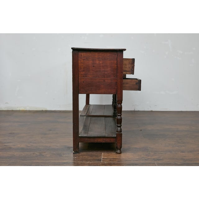 An English late Georgian oak dresser base from the 19th century with bone inlay. This 19th-century English oak dresser...