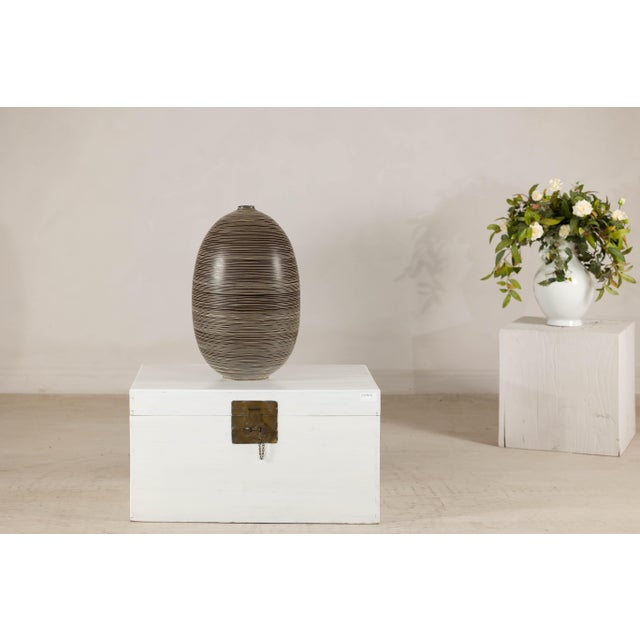 This large-scale artisan ceramic vase presents a refined, sculptural silhouette defined by its generous ovoid form and...