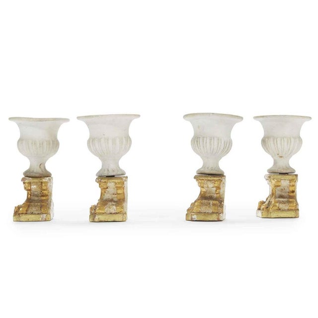 Four Neoclassical Table Decorations composed of four carved, lacquered and gilded wooden bases and a Medici vase in...