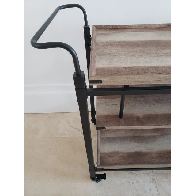 Black metal and wood modern bar cart. 3 wood shelves, opposing handles, on wheels. Excellent condition. Sturdy.