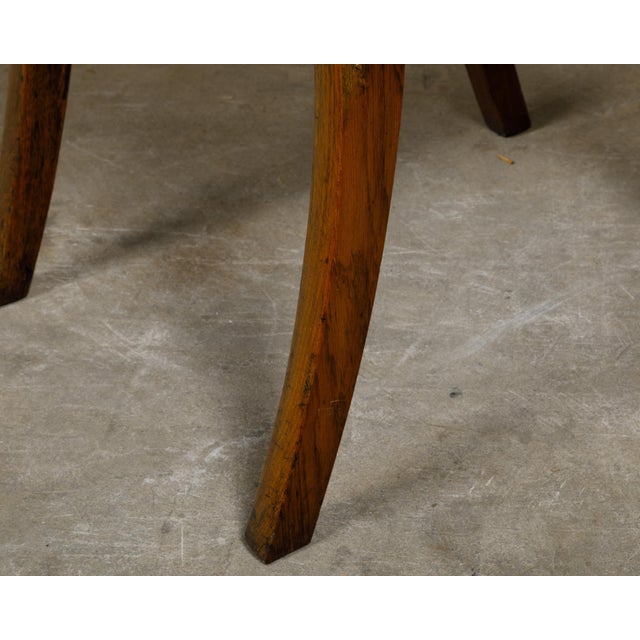 A pair of English oak stools from the 19th century with saber legs and custom upholstery. This pair of English oak stools...