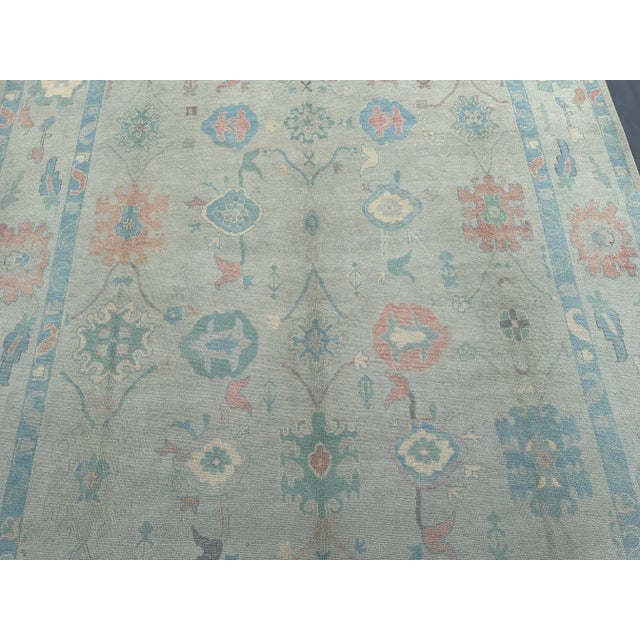 This handmade wool rug showcases the timeless beauty of Oushak design with a faded, vintage-inspired palette of ivory,...