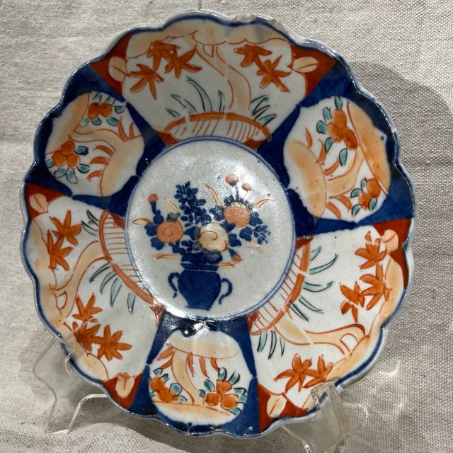 19th century Japanese Imari plate. Scalloped rim, central floral in vase, border interspersed with foliage and landscape...