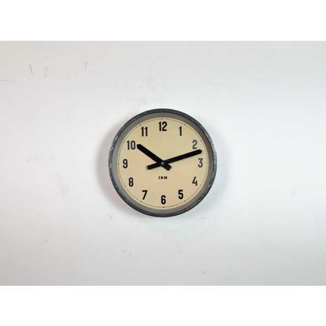 This wall clock was produced by IBM in USA during the 1950s. It features a dark grey metal frame, iron dial, aluminium...