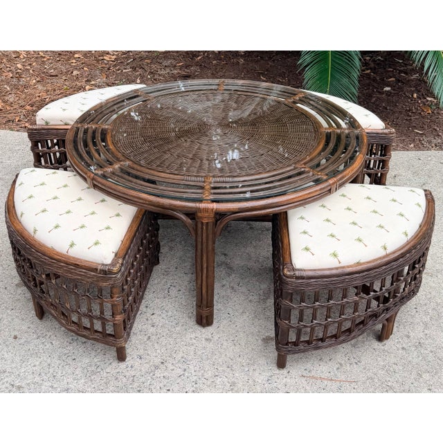 This is a vintage rattan round cocktail or game table with four benches, finished in dark brown rattan with palm-patterned...