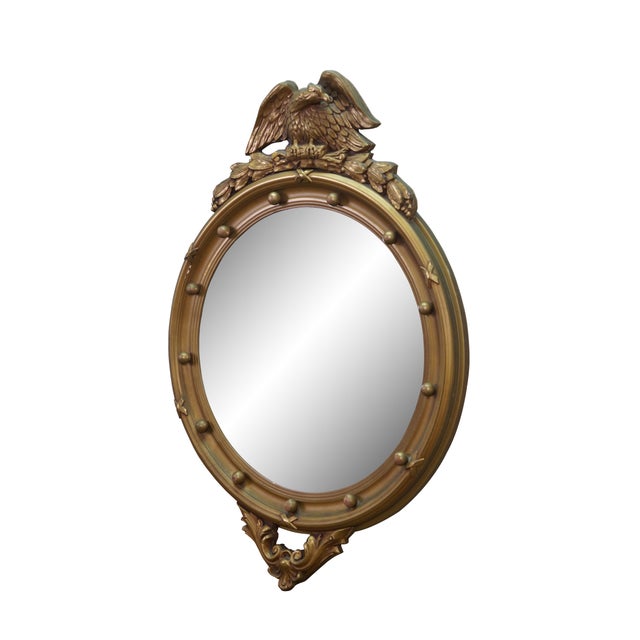 Antique gold giltwood convex bullseye wall mirror featuring a round frame varved with and American eagle with wings...