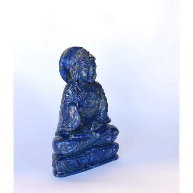 A finely hand-carved Buddha sculpture crafted from natural lapis lazuli. Buddha is seated in a dhyana asana upon a...