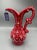 Vintage-style red decorative pitcher with an elegant sculptural silhouette, scrolling handle, flared spout, and raised...