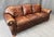 This Thomasville brown leather sofa features a classic three-seat design with generously padded cushions, rolled arms, and...