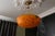French art deco pendant light from the 1930s, featuring a deep mottled orange glass bowl suspended by sculptural brass...