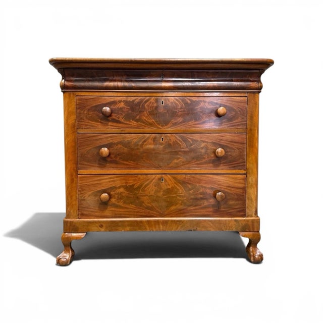 A stunning 19th-century chest of drawers. Featuring dramatic tiger maple veneer, elegant scrolling front rail, and bold...