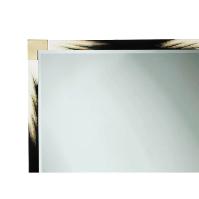 A large modern black lacquered and faux horn mirror, the rectangular top with brass edged corners, enclosing a bevelled...