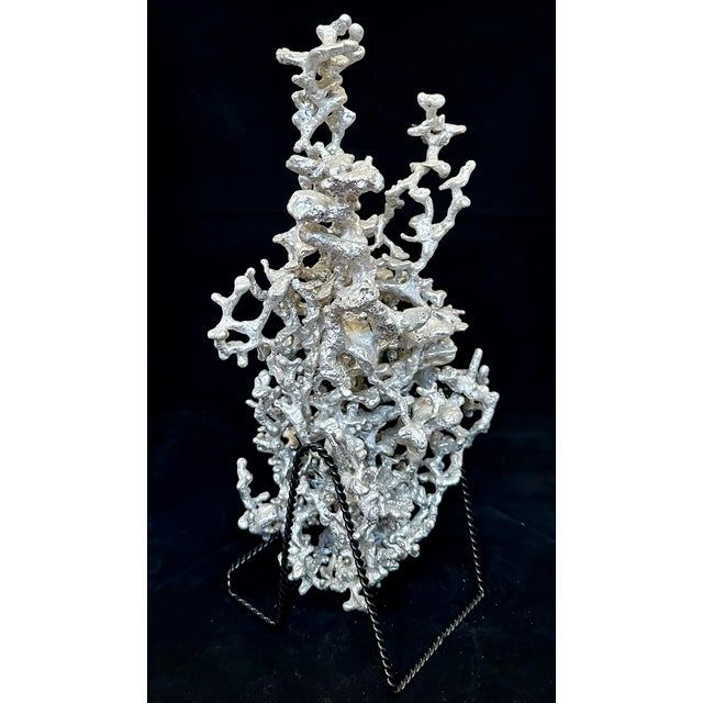A striking cast aluminum ant colony sculpture, capturing the intricate subterranean architecture of tunnels and chambers...