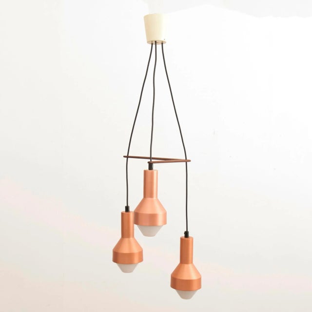 A mid century three tier pendant comprising idman k2-133 copper anodised shades with a teak boomerang holder designed by...