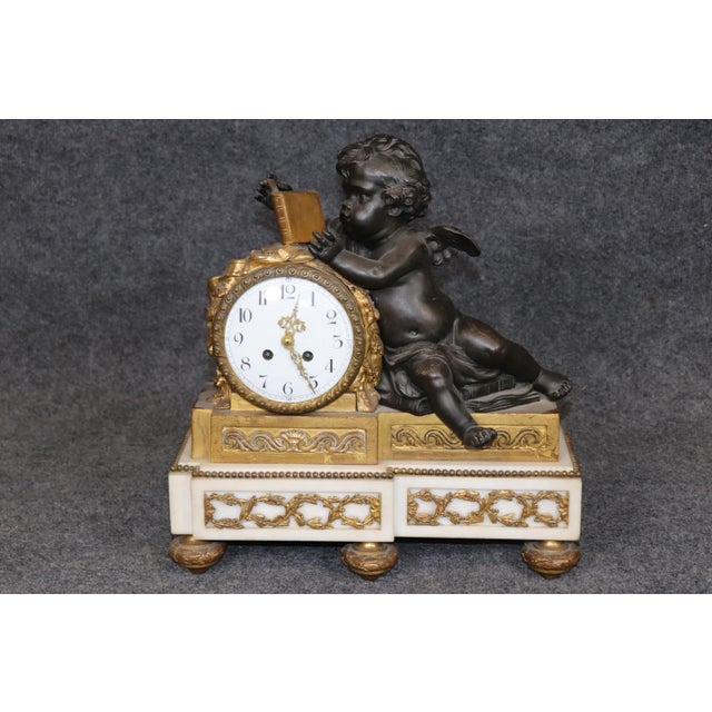 French Three-Piece Bronze and Marble Clock Garniture with Putti and Cherubs, circa 1920 This impressive French three-piece...