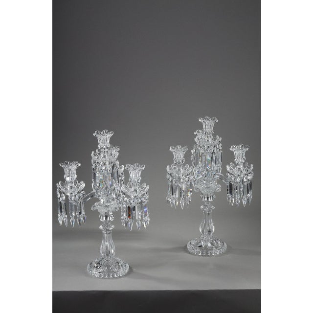 Pair of Baccarat four-light, two-tier crystal girandoles. They are decorated with geometric crystal pendants, the shafts...