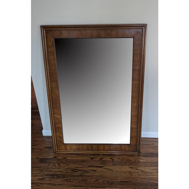 This wall mirror was made by Drexel in 1980 and is from their campaign-style Accolade II collection. Beveled mirror glass...