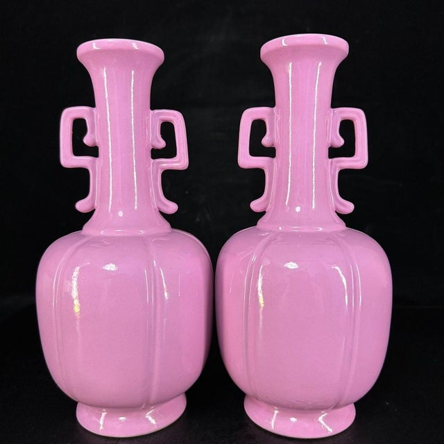 A lovely pair of Chinese monochrome porcelain vases featuring a vibrant, glossy pink glaze. The vases have a faceted,...