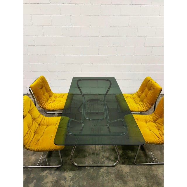 Table with six armchairs, featuring a chromed steel frame, black glass top, and six chairs upholstered in short-pile...