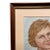 A mid-century modern portrait painting of a woman on blue silk. This portrait is professionally framed in a rectangular...